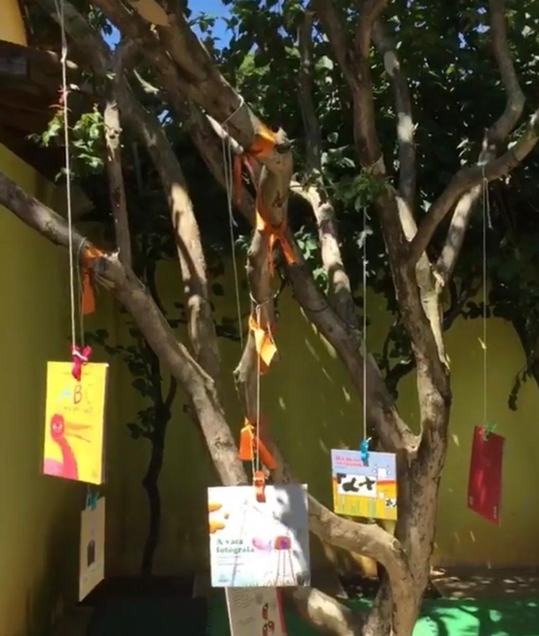 Árvore com livros infantis pendurados no espaço externo
