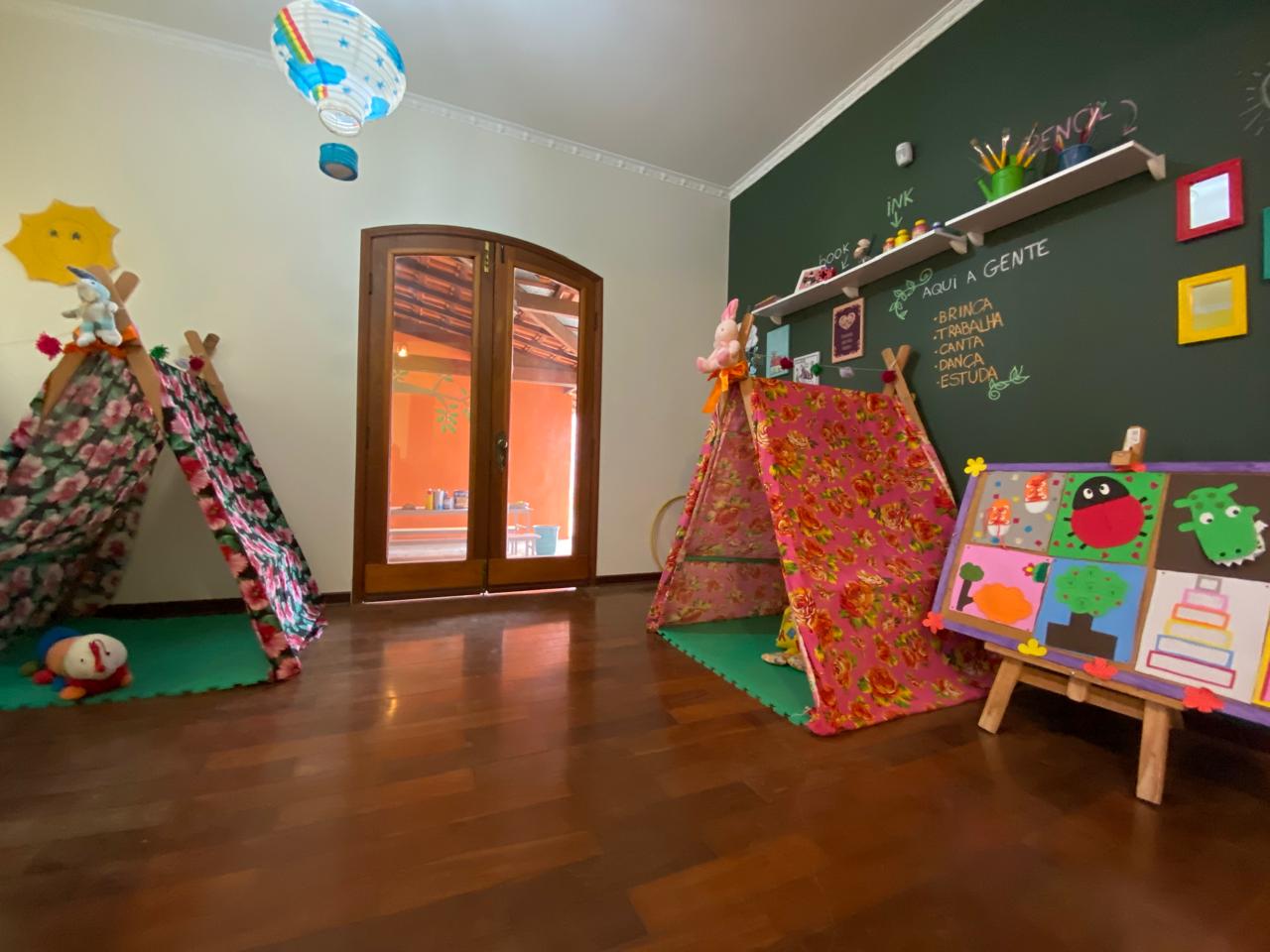 Sala do Colégio Pingo de Gente com cabanas, painel pedagógico e brinquedos