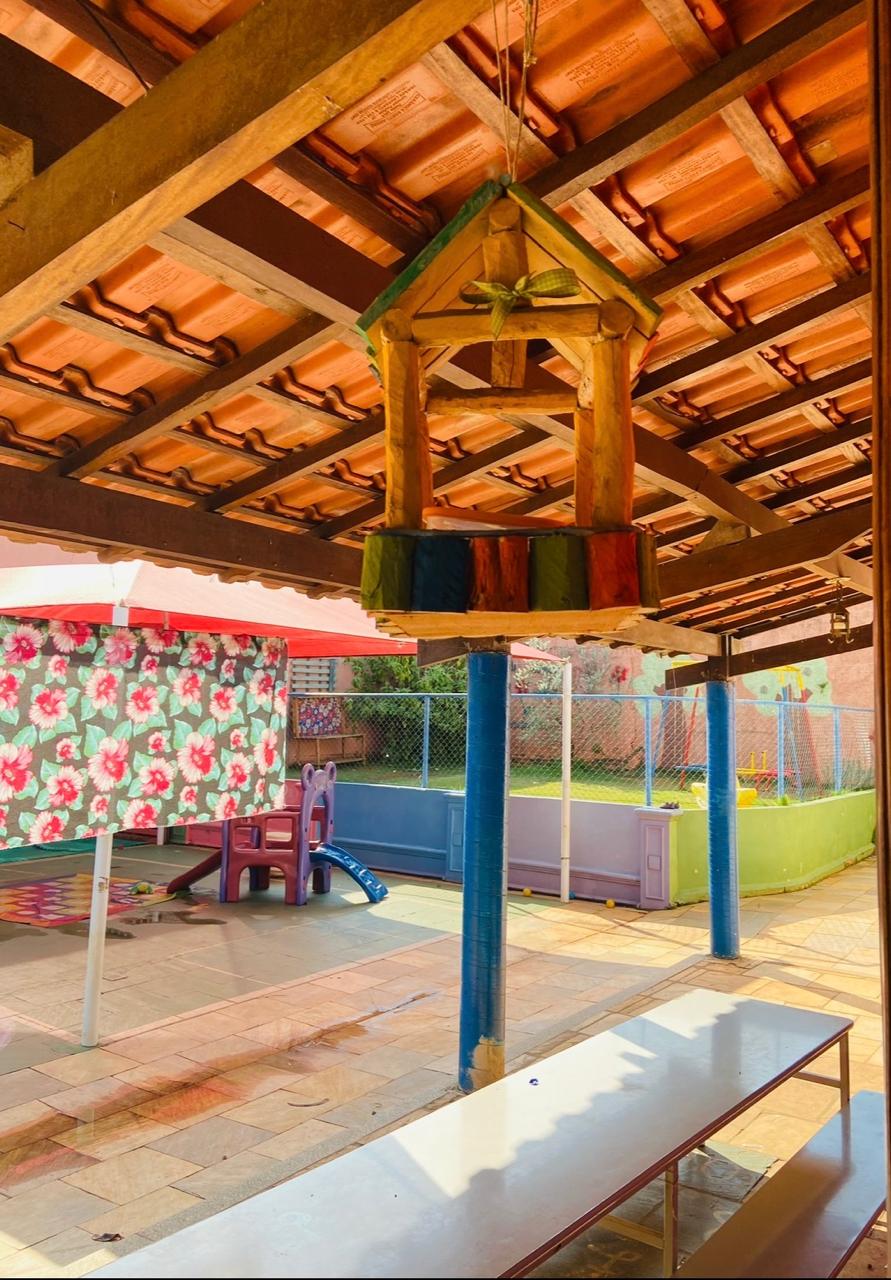 Pátio coberto com brinquedos e casinha suspensa de madeira
